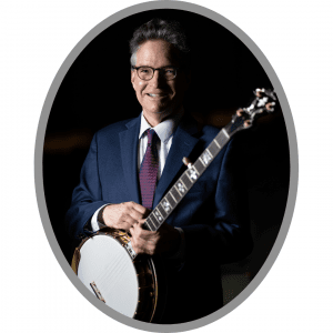 Smiling man standing with a banjo wearing a suite